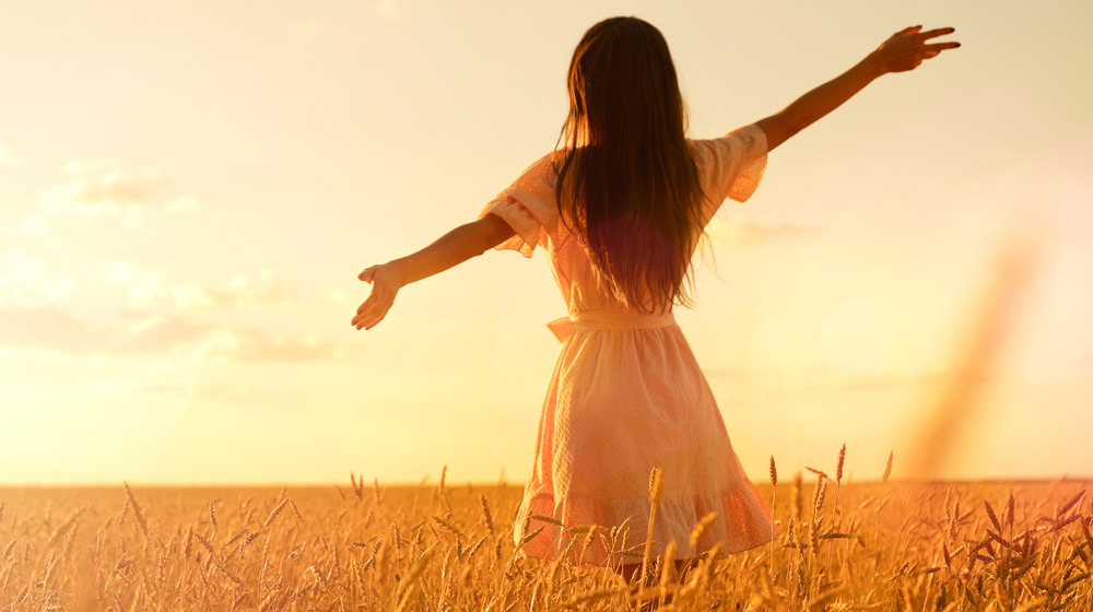 Person with long hair standing in a wheat field