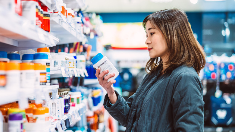 A woman in the grocery checking supplement bottles