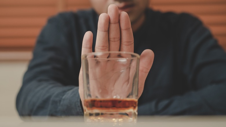 Man pushing away glass of liquor