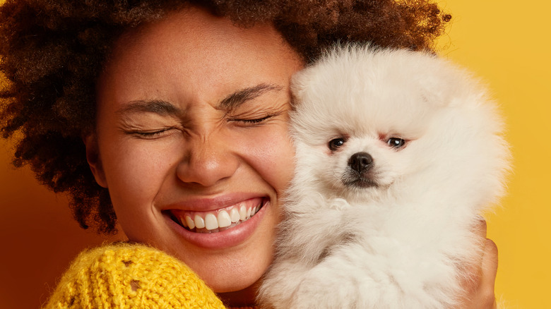 curly-haired woman hugging dog