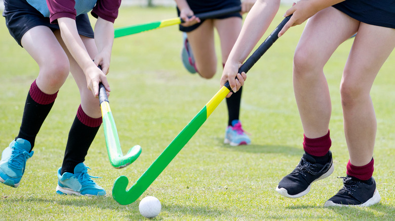 Female students playing field hockey