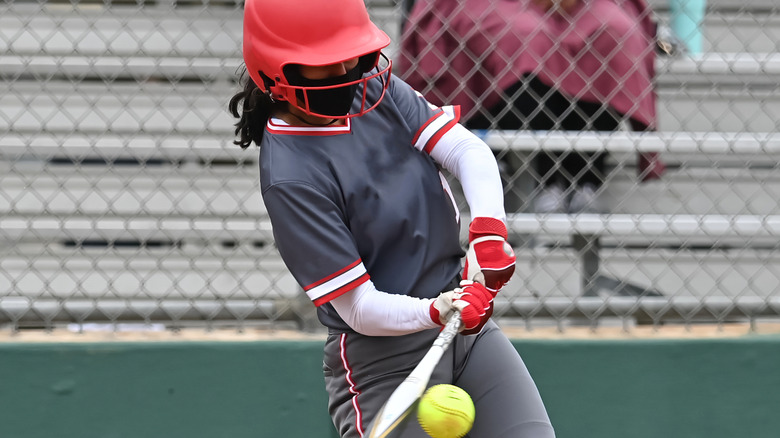 A softball player hitting the ball