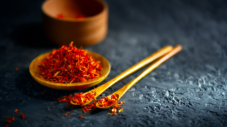 a wooden plate and two spoons filled with saffron 