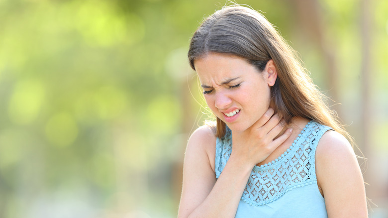 woman with hand on throat