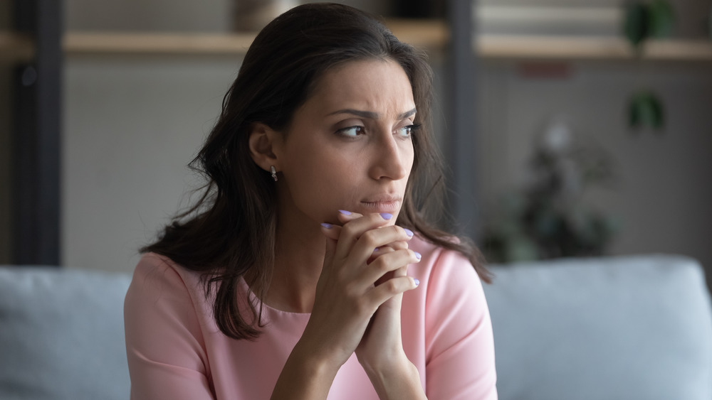 Person sitting with fingers intertwined looking off into the distance