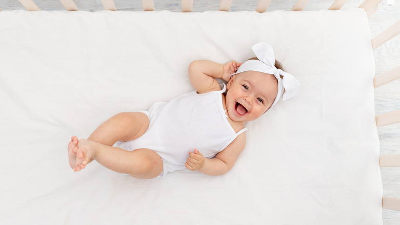 overview of a smiling baby in lying in their crib 