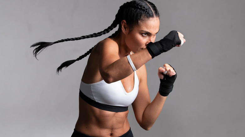 Woman in boxing gloves prepared right hand punch.