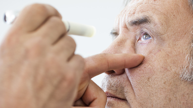 Close-up of hand holding onto a light and shining it into a patient's eye