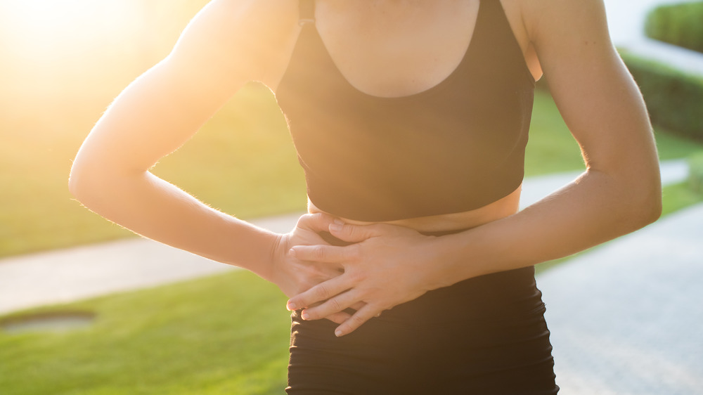 woman holding stomach during run