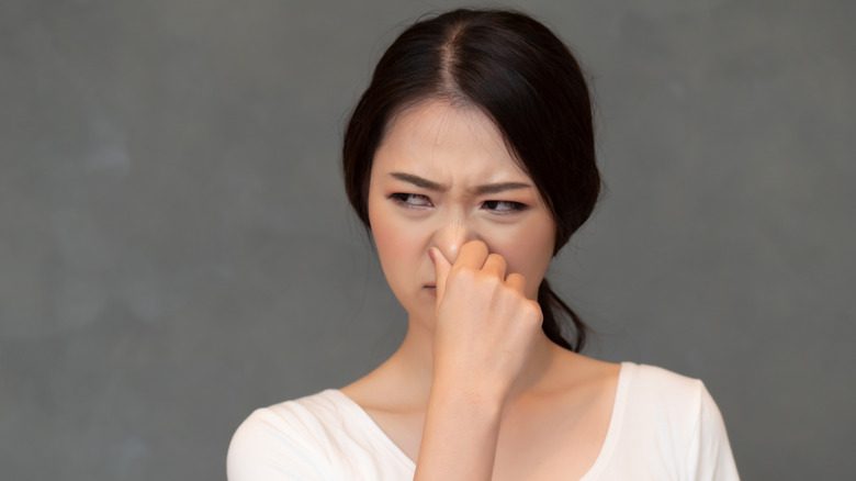 woman pinching her nose and grimacing