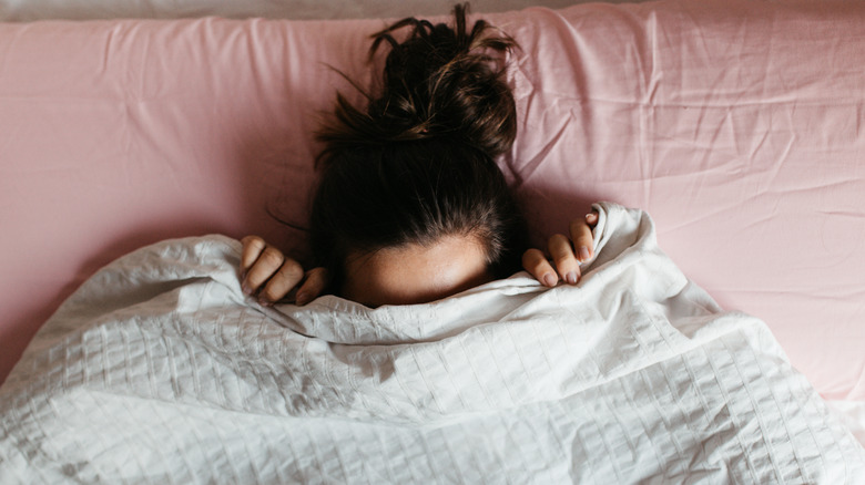 Woman hiding under blanket 