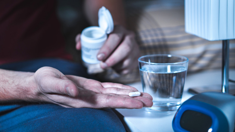 Man preparing to take sleep medication pills 