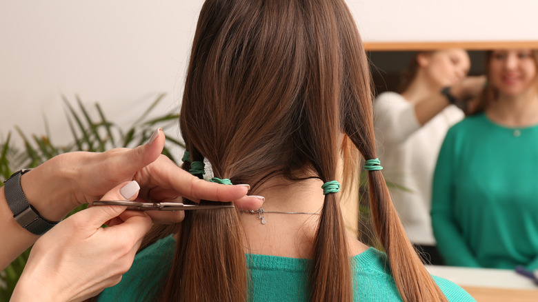 Hands holding scissors cutting a woman's hair for donation