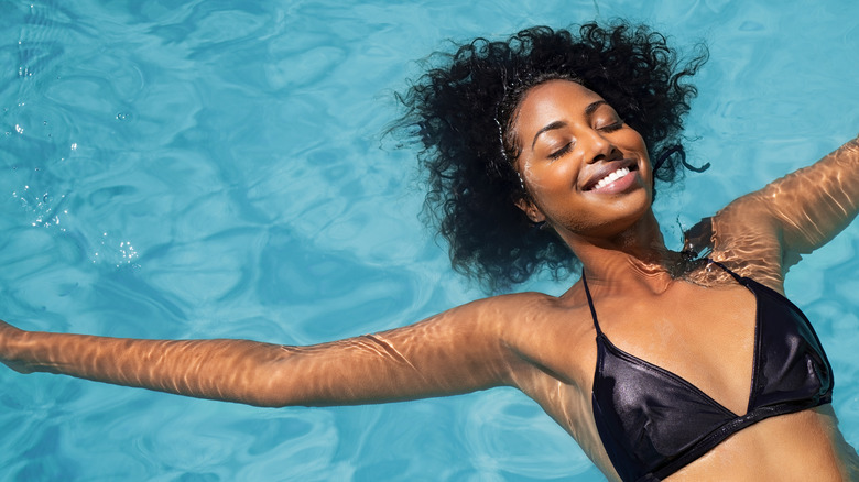A woman floating in a pool and smiling