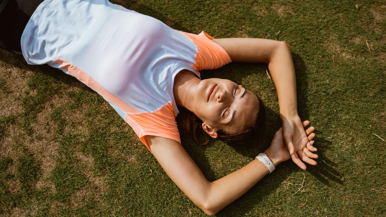 woman laying on the grass in workout clothes post-workout 