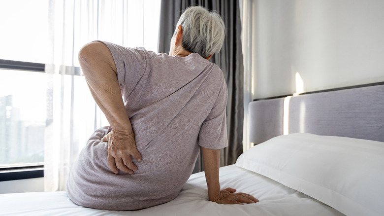 Elderly woman waking up and holding back