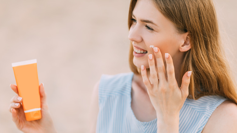 A woman applying cream to her face