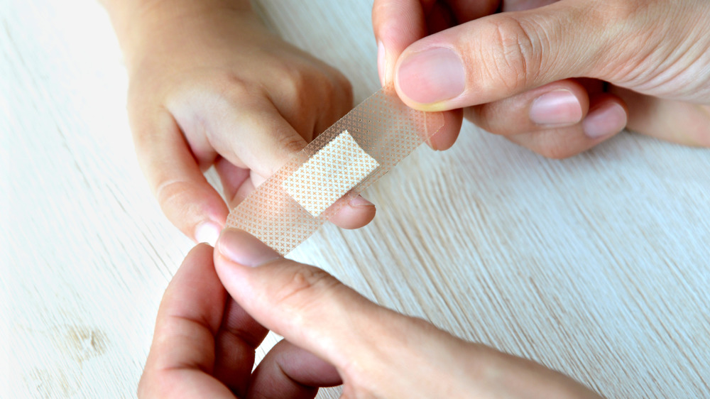 An adult puts a bandage on a child's finger