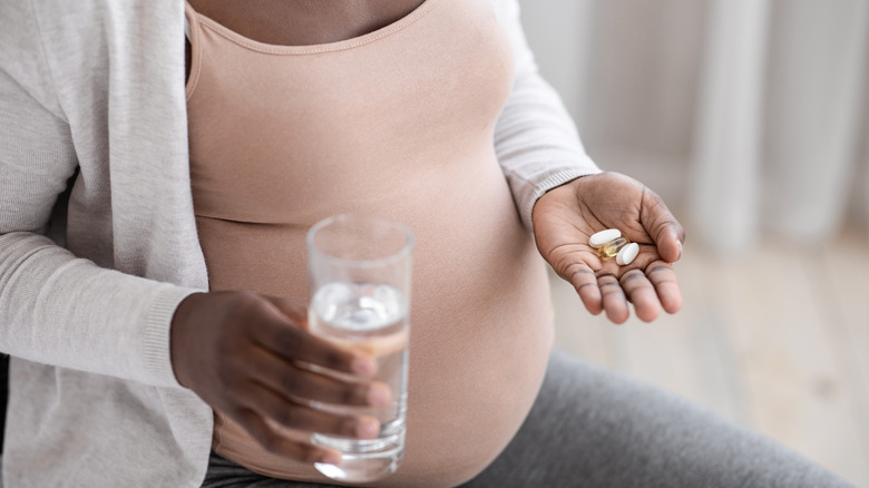 Pregnant woman holding prenatal vitamins