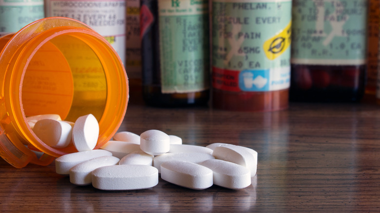 Orange prescription bottle tipped over and spilling white pills onto surface