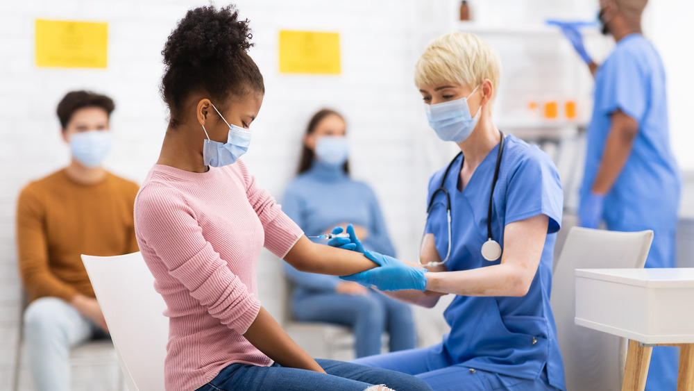 Nurse giving teen girl COVID-19 vaccination