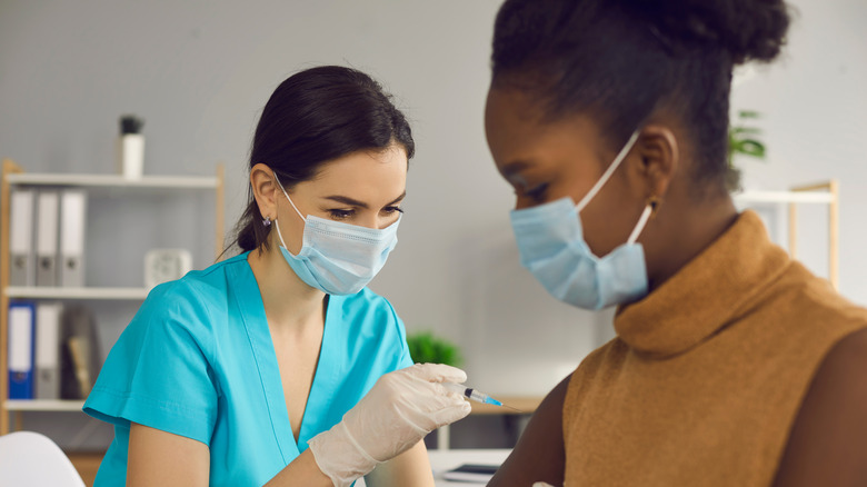 A healthcare worker administering a vaccination shot to a woman