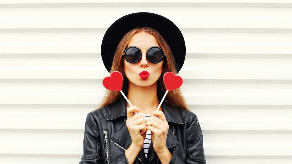 Woman holding up two hearts next two her heart shaped lips 