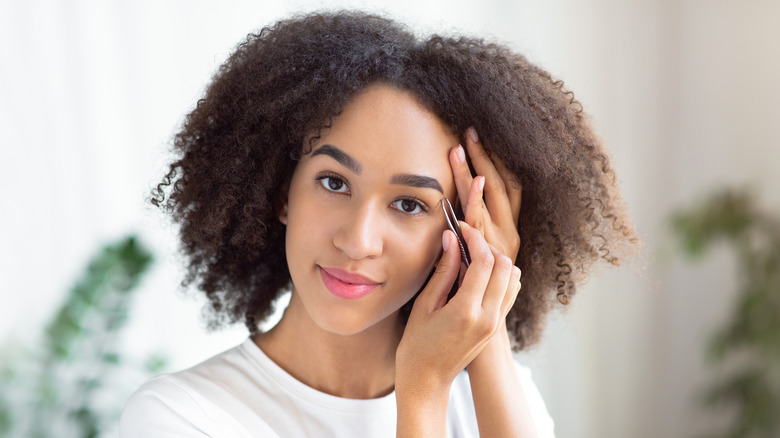  A woman shaping her brows at home