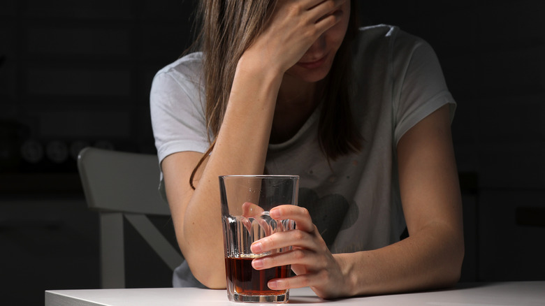 Sad woman with a glass of whiskey in her hand