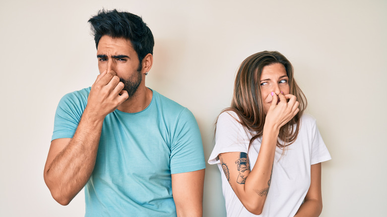 Man and woman holding their noses over smell