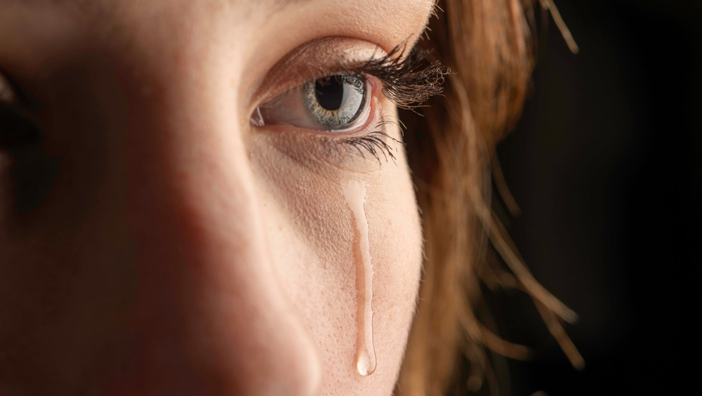 Closeup of blue eye with a tear falling