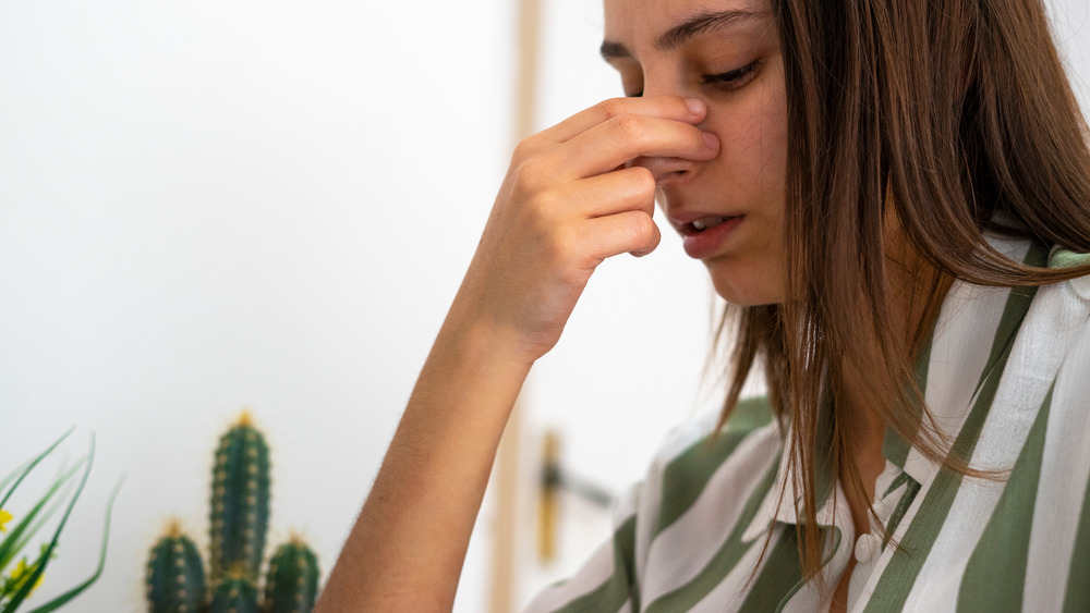 Woman looking down and pinching the bridge of her nose 