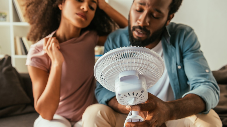 Overheated couple with handheld fan 