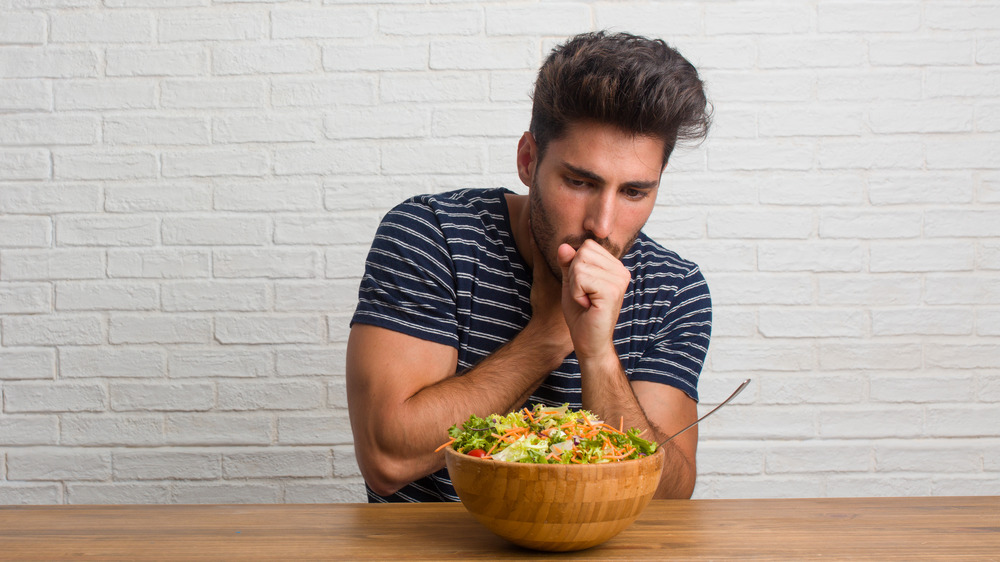 Man holding back from gagging after eating salad
