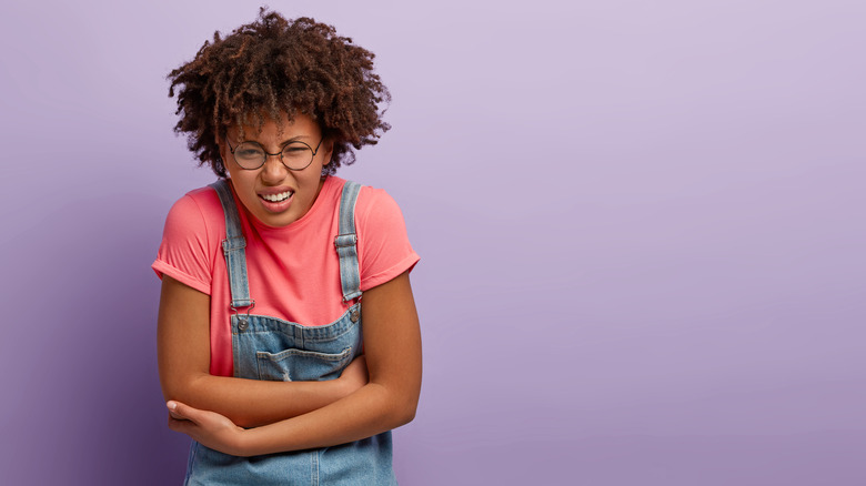 girl with glasses holding stomach from pain