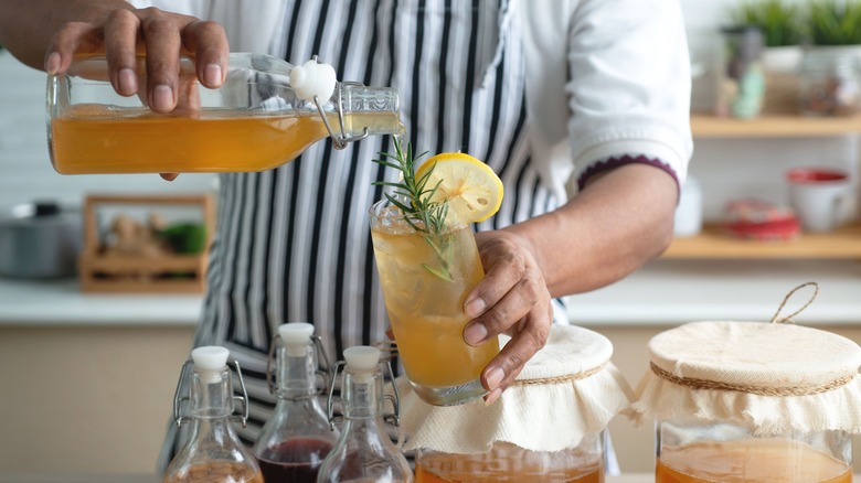man pouring kombucha into glass