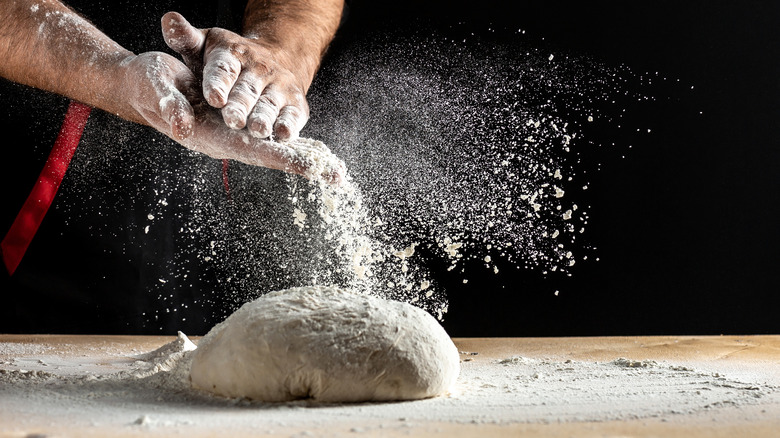 Pizza dough with flour in the air