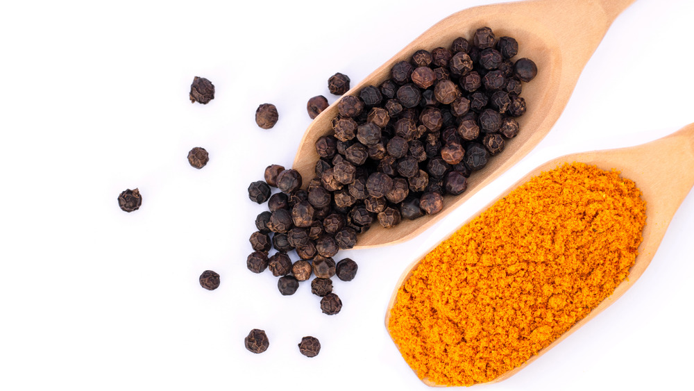 Turmeric and black pepper in wooden spoons
