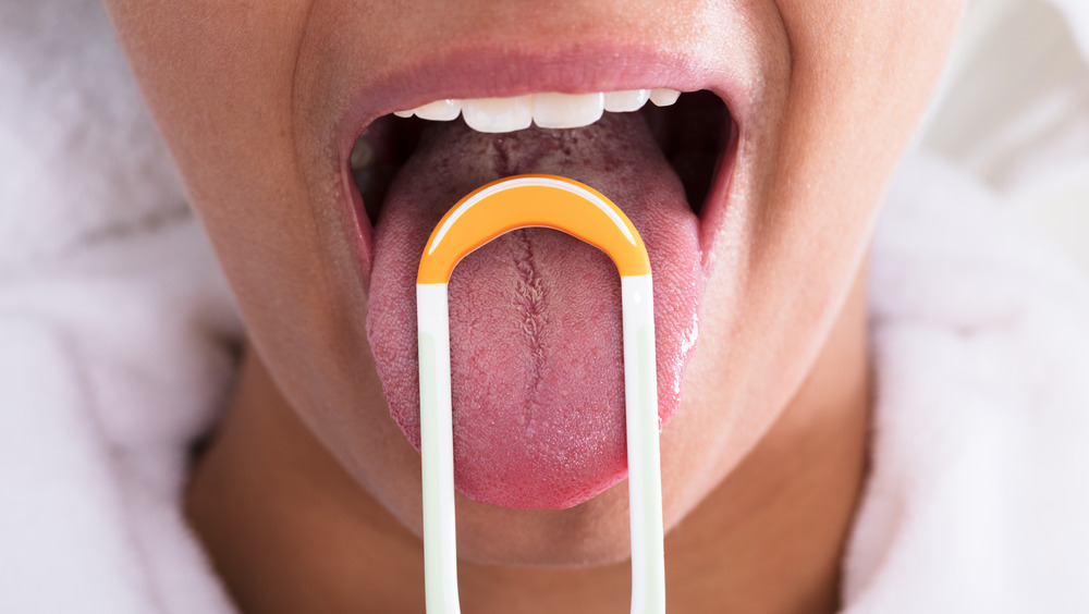 Woman cleaning her tongue with scraper