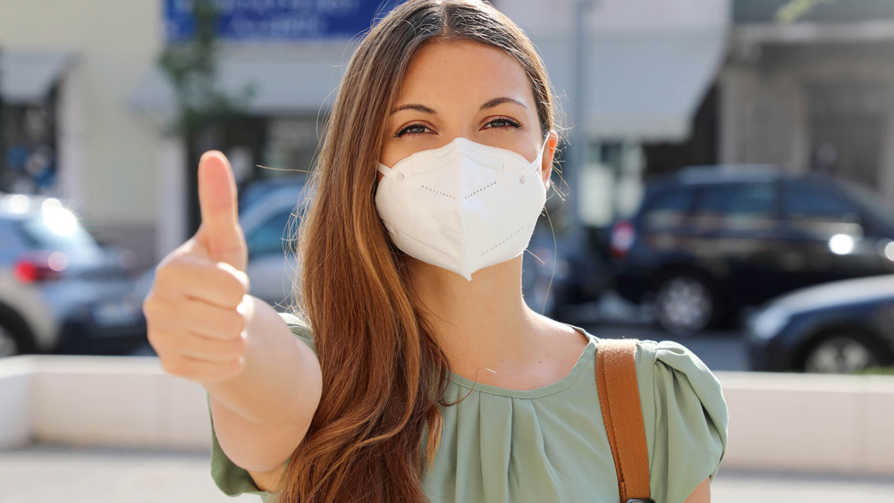 woman giving thumbs up wearing mask