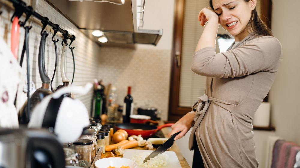 Woman crying while cutting onions