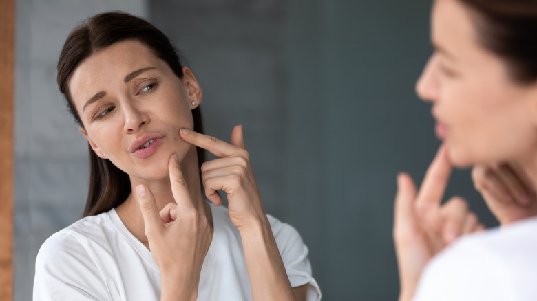 A woman looks at her acne