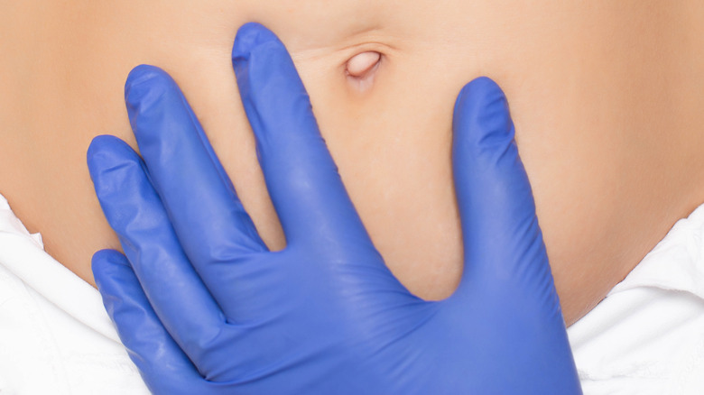 Gloved hand near belly button