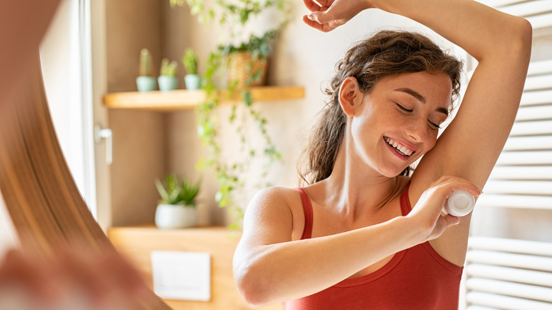 Woman happily applying deodorant 