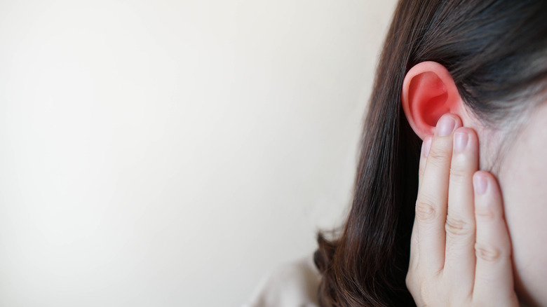 The side of a woman's head as she touches her ear