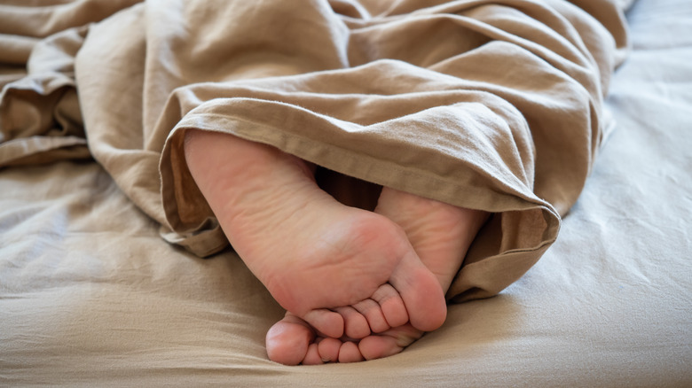 feet seen under blankets on bed