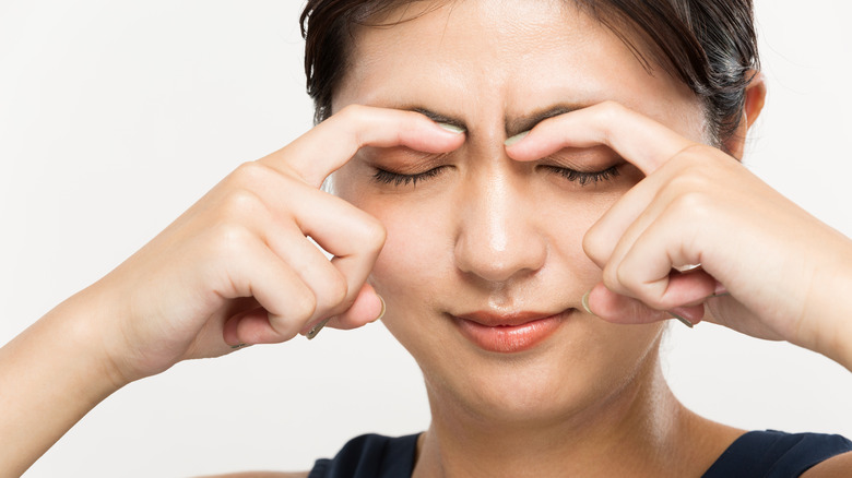 Asian woman pressing her eyelids