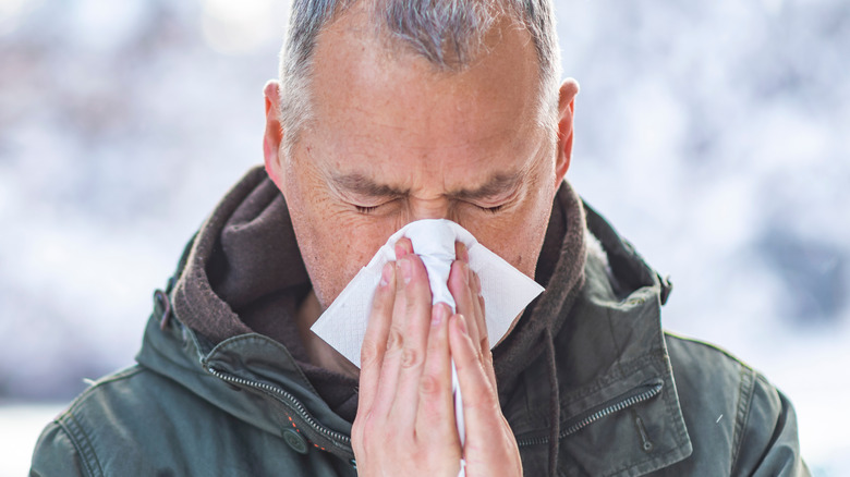 Older man blowing nose