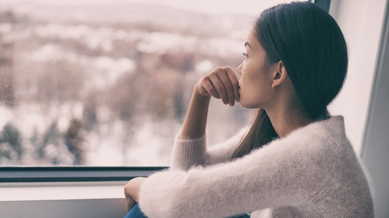 pensive woman staring out her window