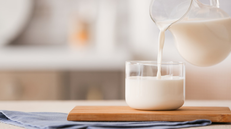 Pouring milk into glass on table